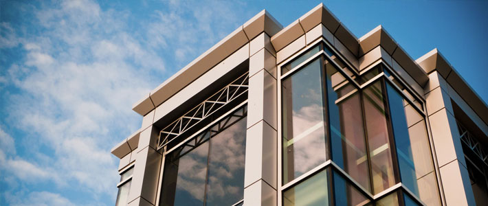 Low Angle View of Metal and Glass Office Building Against Blue Sky and White Clouds